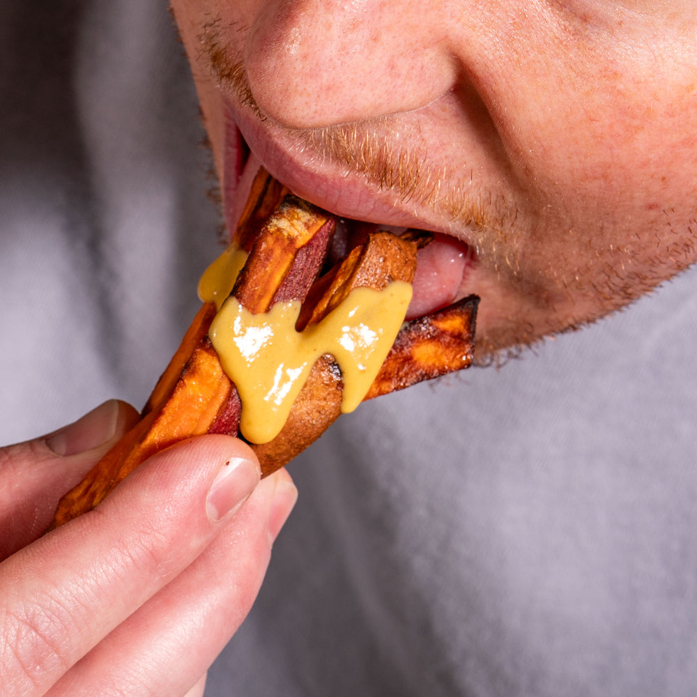 Yellowbird Small Batch Garlic Shiitake Hot Sauce drizzled onto sweet potato fries about to be eaten