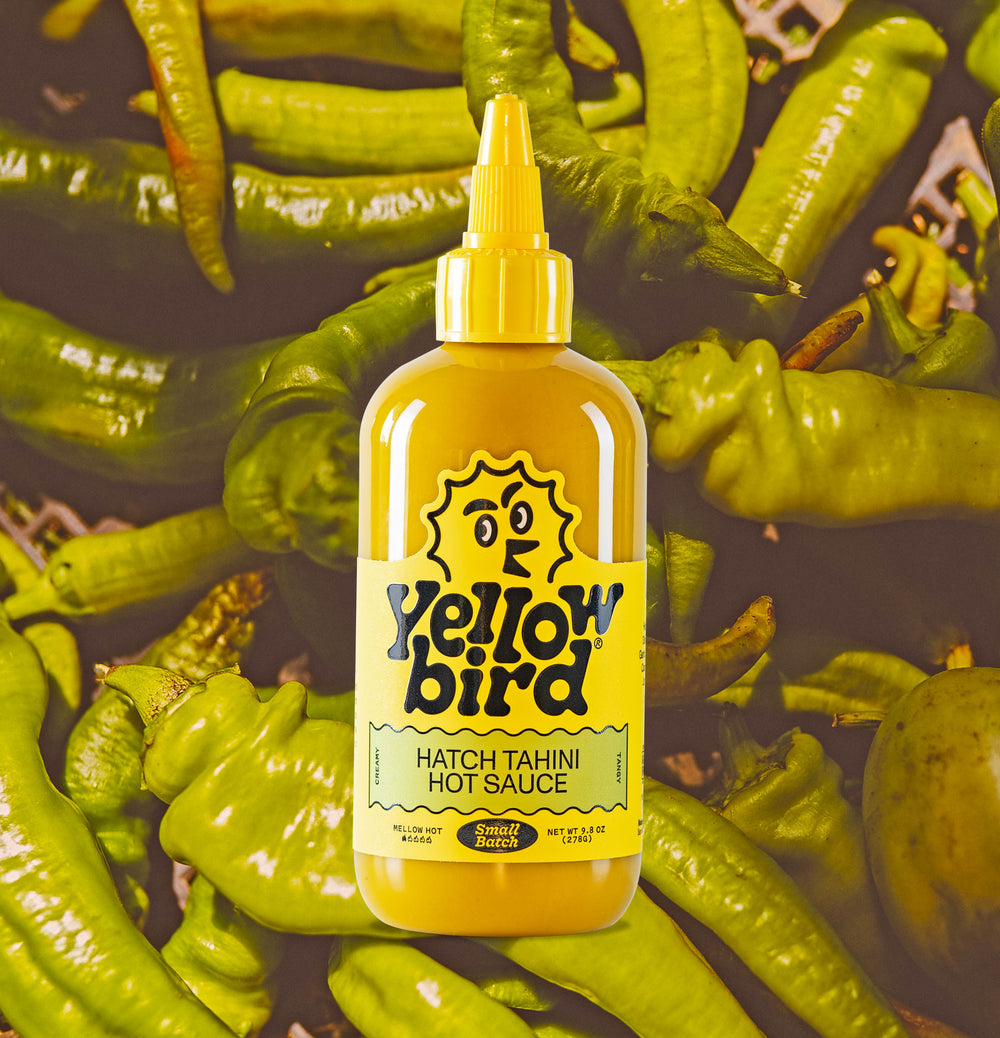 Yellowbird Hatch Tahini Small Batch Hot Sauce 9.8 oz. with fresh hatch chilis background