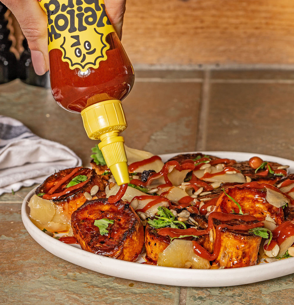 Yellowbird Organic Sriracha drizzled onto glazed roasted sweet potatoes