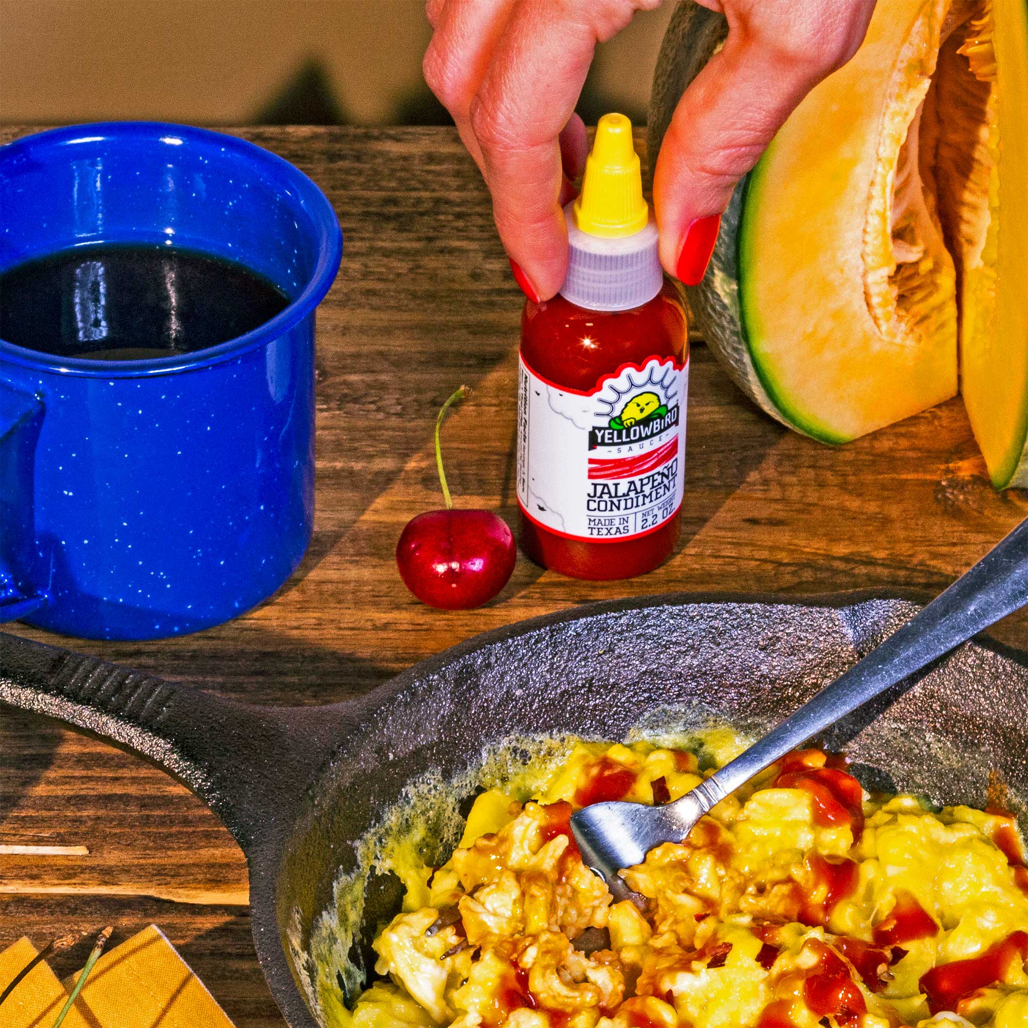 Yellowbird Classic Jalapeño Hot Sauce on scrambled eggs at a camping table